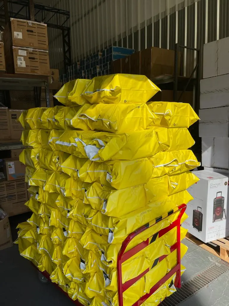 Paquetes envueltos en amarillo sobre un carro, en un depósito de Unibox