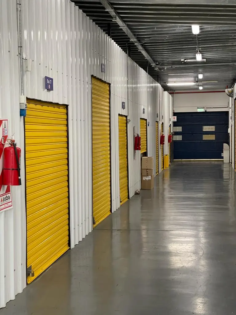Pasillo de bauleras de Unibox, con persianas amarillas y matafuegos